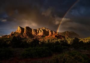 Радуга на грозовом небе на фоне гор.